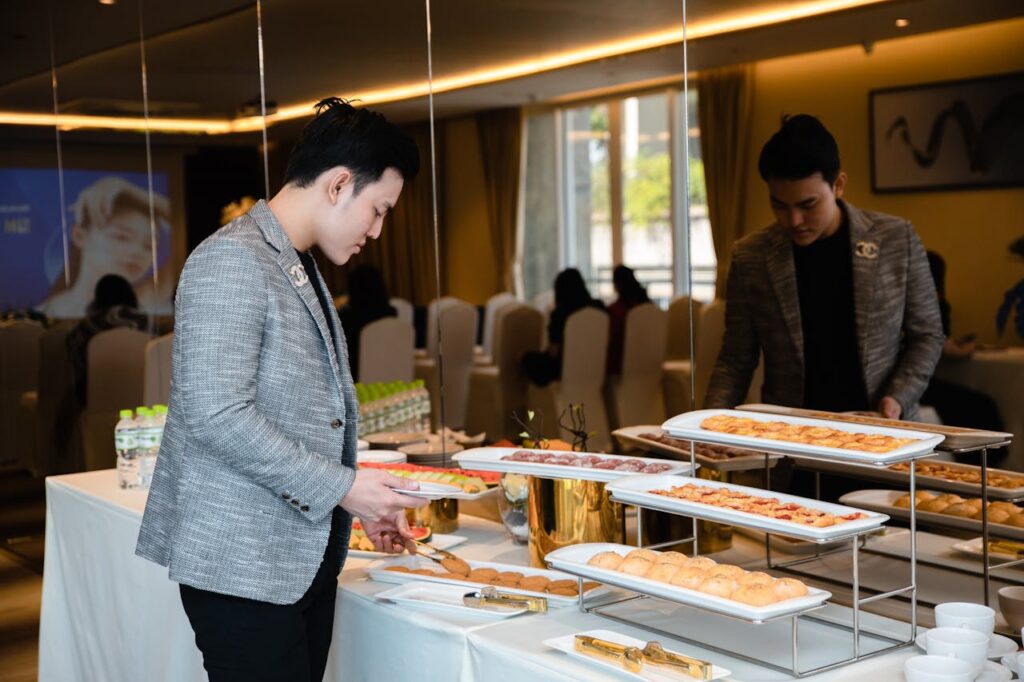 pexels-photo-32441077 Man selecting pastries from a buffet at a corporate event indoors.